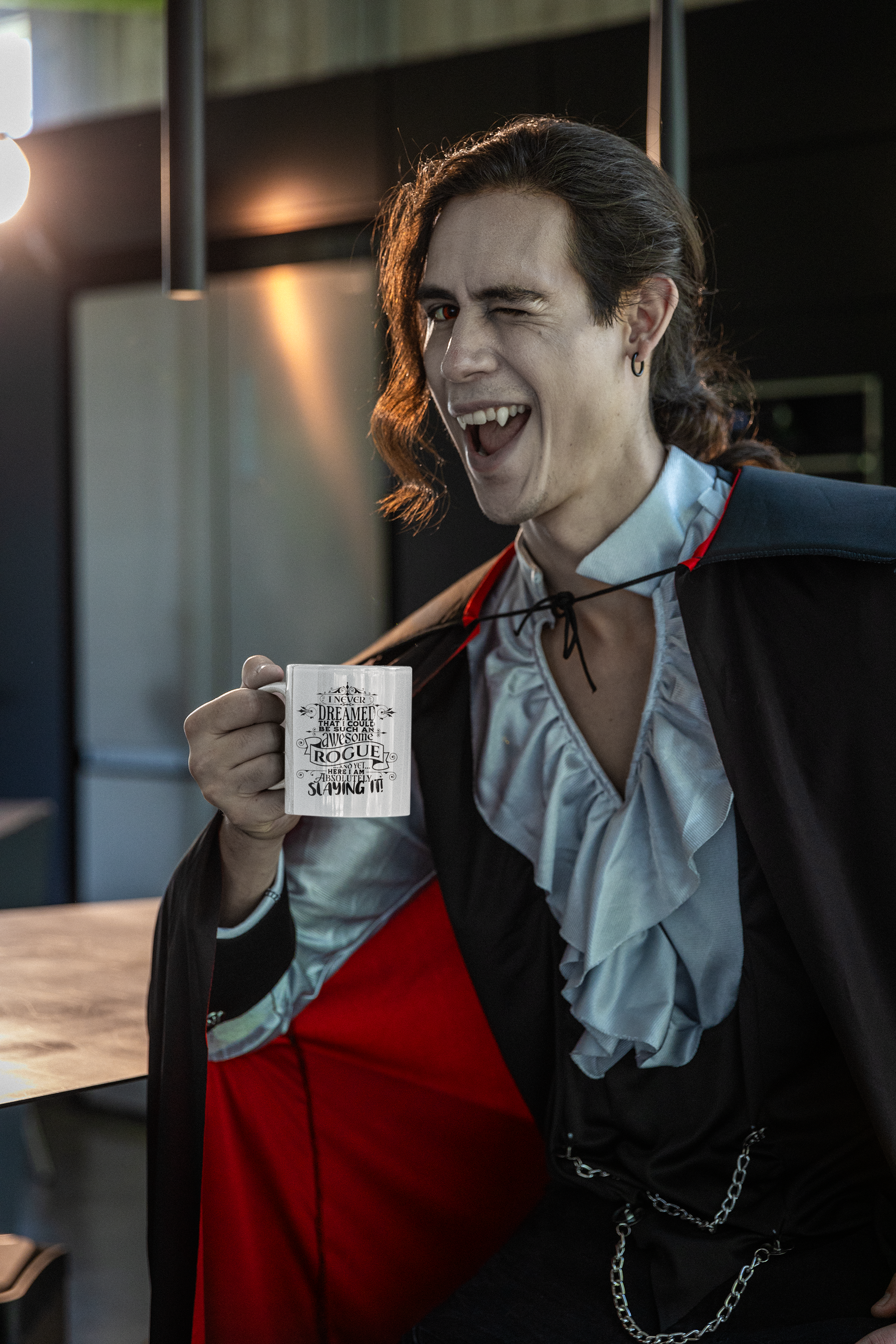 a man dressed in a dracula costume holding a coffee mug