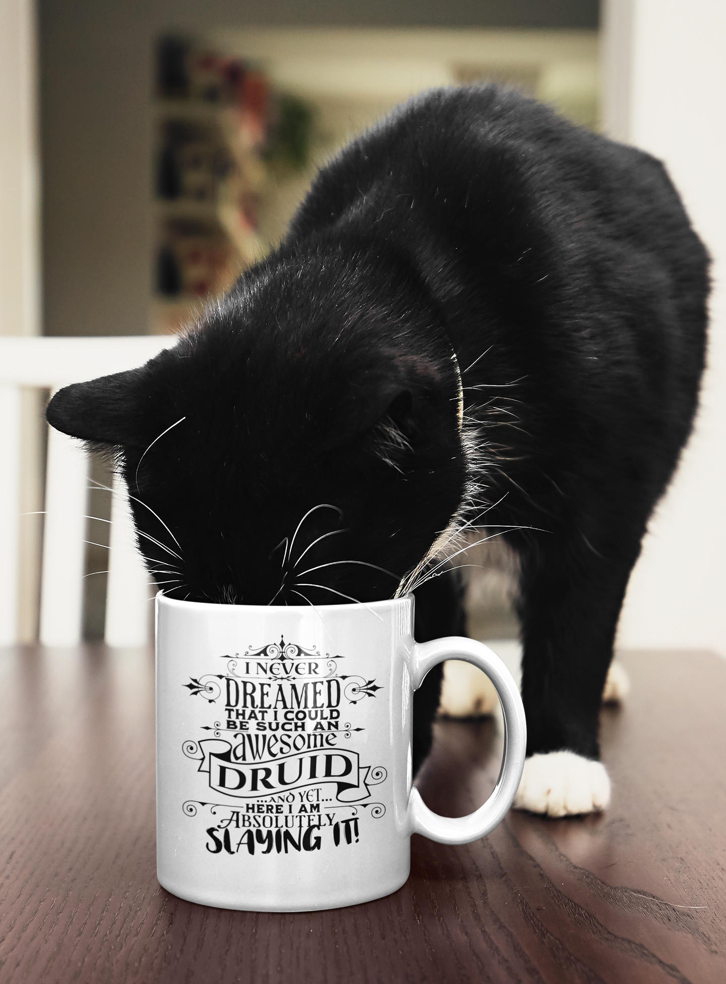 a black and white cat drinking out of a coffee mug